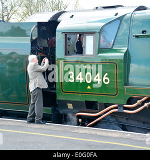 Uomo con macchina fotografica scattare foto ravvicinata della pedana del motore a vapore conservato 34046 Braunton durante la fermata Banbury stazione ferroviaria Oxfordshire Inghilterra Regno Unito Foto Stock