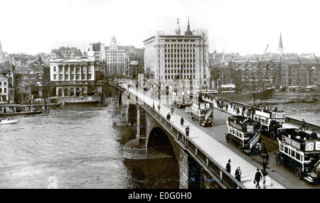 L'immagine del 1927 del traffico stradale sul London Bridge mostra un ambiente urbano affollato con autobus, pedoni e veicoli che attraversano l'iconico ponte. Questa fotografia cattura il traffico e il trambusto del sistema di trasporto di Londra durante la fine degli anni '1920, riflettendo la crescita e la modernizzazione della città. Foto Stock
