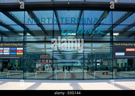 Entrata del Terminal Nord dell'Aeroporto di Gatwick Londra e cartello passeggeri all'interno visti attraverso i riflessi parete di vetro traslucido Crawley West Sussex Inghilterra Regno Unito Foto Stock