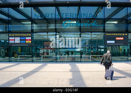 Viaggiatore a piedi verso il check-in presso il London Gatwick Airport North Terminal Foto Stock