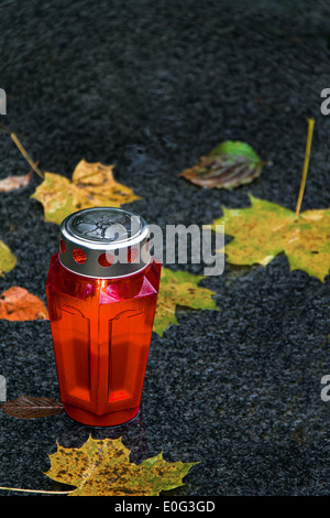 Un grave alla luce di Ognissanti in autunno con fogli, ein Grablicht zu Allerheiligen im Herbst mit Blaettern Foto Stock