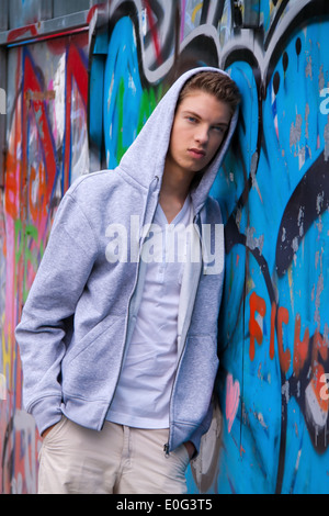 Un fresco guardando giovane uomo prima di graffiti, Ein cool blickender Jugendlicher Mann vor Graffiti Foto Stock