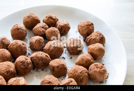 In casa tartufi di cioccolato in polvere di cacao su piastra bianca Foto Stock