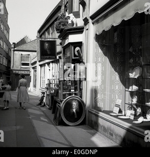 1950s. Foto storiche di una strada laterale, Brighton, Inghilterra, mostra una donna e bambino oltrepassando il Compton negozio di antiquariato. Foto Stock