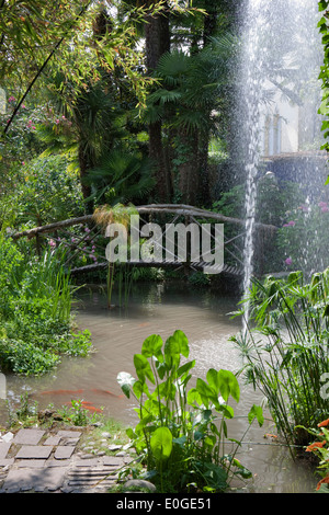 Ponte attraverso un laghetto con fontana a Andre Hellers' giardino, Giardino Botanico, Gardone Riviera sul lago di Garda, Lombardia, Italia, UE Foto Stock