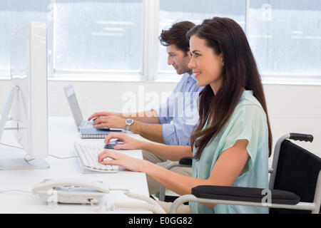 Lavoratore in carrozzella lavorando sul computer Foto Stock