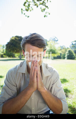 Elegante uomo soffia il naso nel parco Foto Stock