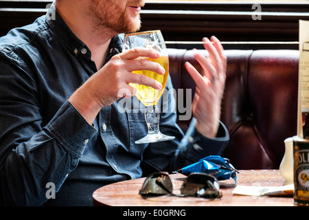 Un uomo in un pub bevendo birra lager. Foto Stock
