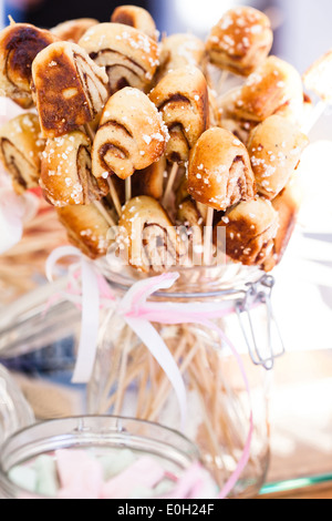 Primo piano di piccole dimensioni snack ciambelle alla cannella su bastoni in un vasetto di vetro con nastro decorativo legato in prua Foto Stock