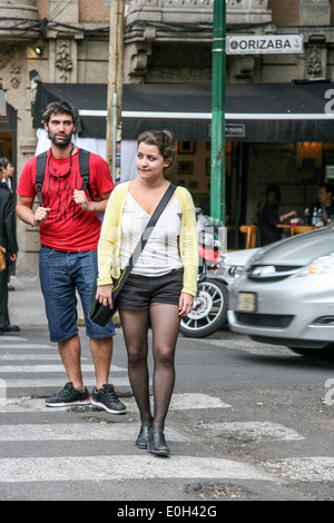 Giovane uomo ammira Pretty girl attraversando Roma Street indossare pantaloncini corti Sheer black calze e scissione moderata Città Del Messico Foto Stock