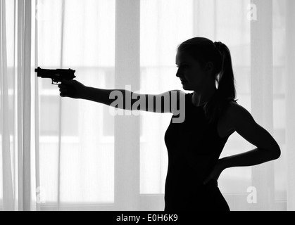 Silhouette della ragazza con una pistola Foto Stock