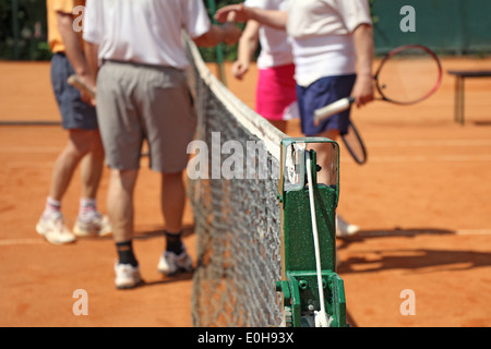 Doppio misto i giocatori di tennis in piedi dalla rete sul campo da tennis Foto Stock