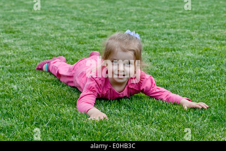 Ritratto di un sorridente bambina, giacente su erba verde Foto Stock