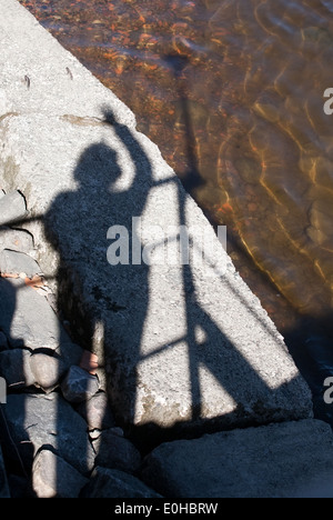 Closeup ombra nera della donna in piedi sul terrapieno e agitando la mano Foto Stock