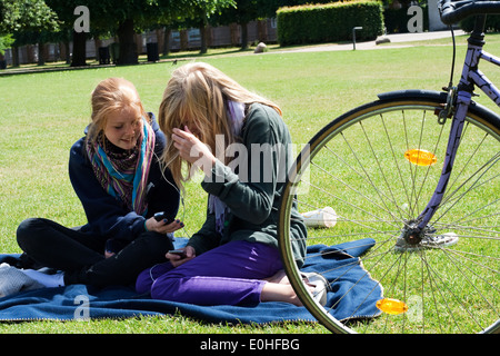 Due ragazze chat e utilizzare il loro telefono mobile Foto Stock