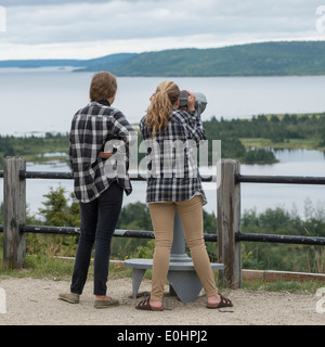 Ragazze guardando bay view attraverso una gettoniera binocolo, Joey's Lookout, gambo, Terranova e Labrador, Canada Foto Stock