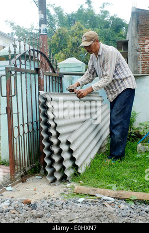 Lavoratore locale manipolazione di fogli di amianto ancora in uso comune durante la costruzione in Indonesia Foto Stock
