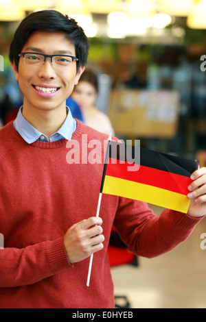 Sorridente studente asiatico holding bandiera della Germania Foto Stock