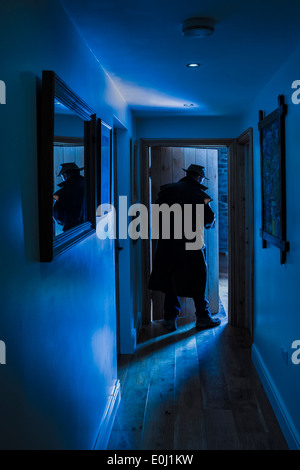 Un uomo che indossa un cappello e impermeabile a lungo di entrare in una stanza. Foto Stock