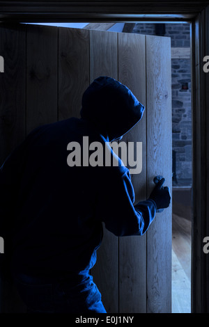 Un anonimo maschio con cappuccio di entrare in una stanza. Foto Stock