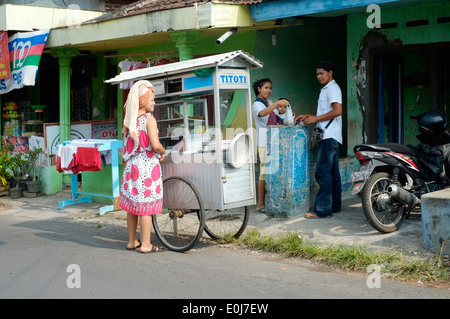 Villaggio donna acquisto bakso snack da venditori ambulanti carrello in Giava Est Indonesia Foto Stock