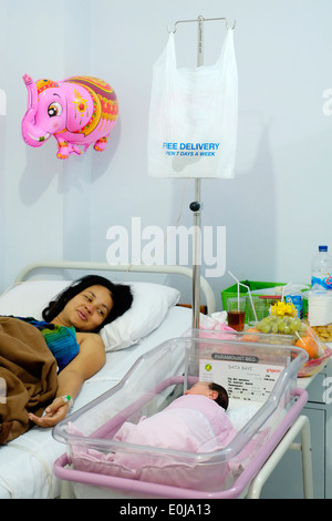 Madre guarda con orgoglio alla sua neonata figlia del sonno dal suo letto dopo il taglio cesareo in un ospedale di malang indonesia Foto Stock