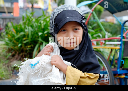 Piccola ragazza di strada portando un enorme sacco di raccolta di rifiuti di plastica da vendere su per il riciclaggio a malang east java indonesia Foto Stock