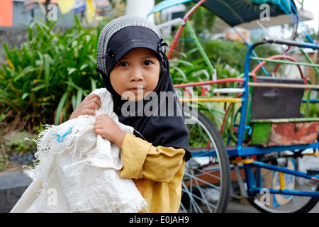 Piccola ragazza di strada portando un enorme sacco di raccolta di rifiuti di plastica da vendere su per il riciclaggio a malang east java indonesia Foto Stock