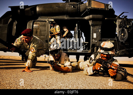 Correre al di fuori di un UH-60 Black Hawk elicottero, soldati iracheni ha colpito la terra e di assumere posizioni di sicurezza durante un corso di formazione per gli ex Foto Stock