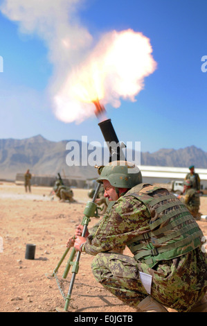 Un esercito nazionale afghano soldato con le armi pesanti plotone, sesto Kandak, bretelle se stesso come un round gli incendi da un 82mm morta Foto Stock