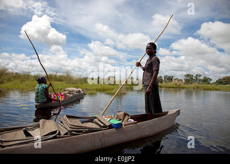 Poler femmina sul loro mokoro tradizionale barca in Okavango Delta, Botswana, Africa Foto Stock