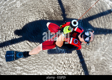 Stati Uniti Coast Guard Petty Officer di prima classe Fogle Bret, un nuotatore di salvataggio, viene issato in un MH-60 elicottero Jayhawk a Costa G Foto Stock