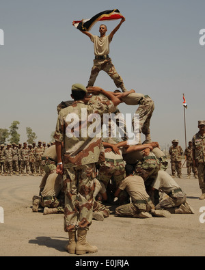 Un iracheno Air Force mandato officer saluta la bandiera irachena come un altro mandato officer sventola la bandiera sulla cima di una piramide umana una Foto Stock