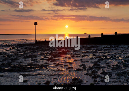 Swalecliffe, vicino a Whitstable Kent REGNO UNITO 15 Maggio 2014: Il sole sorge oltre alla costa del Kent come pressione alta domina il meteo. Le rovine di resti di Herne Bay pier può essere visto all'orizzonte, le sezioni centrali sono state danneggiate dalle tempeste nel 1978 e poi rimosso in seguito Foto Stock