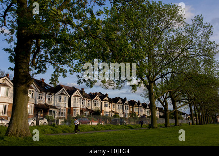 Guardando verso maestosamente alti alberi di cenere e cieli blu, in un epoca Edoardiana casa bifamiliare su Ruskin Park, Denmark Hill, SE24 (il suo codice postale) Sud Londra Inghilterra. Si tratta di un bellissimo pomeriggio invernale in questa città distretto suburbano di Gran Bretagna capitale, a circa 5 miglia a sud del fiume Tamigi. Un pareggiatore scorre oltre la linea elegante del periodo di case che sono state completate nel 1908, l'età dell'edificio innovativo nel nuovo secolo.. (Continua nella descrizione). Foto Stock