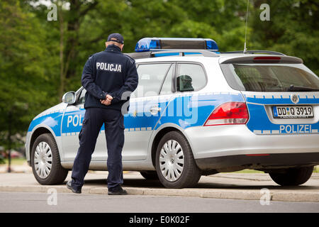 Zgorzelec, Polonia. 15 Maggio, 2014. Un polacco funzionario di polizia guarda a una macchina della polizia tedesca prima della firma la polizia German-Polish accordo sulla cooperazione delle forze di polizia di frontiera e doganali di fronte alla Casa della Cultura di Zgorzelec, Polonia, 15 maggio 2014. Foto: ARNO BURGI/dpa/Alamy Live News Foto Stock