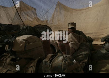 Un Marine con 1° Battaglione, 6° Reggimento Marine si toglie gli stivali e scompostamente sulla sua cremagliera in ombra in un tentativo di Foto Stock