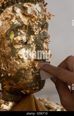 Mettere qualche foglia oro sull'immagine del Buddha Foto Stock