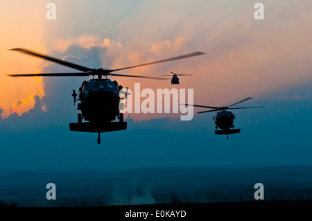 Provincia di Nangarhar, Afghanistan - come il sole si dirige verso l'orizzonte, due UH-60 i falchi nero e un CH-47 Chinook preparare a l Foto Stock