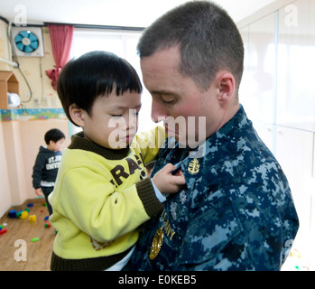 Chief Petty Officer Joseph Hettinger, master-at-arms, detiene un bambino coreano durante una comunità di servizio evento al cantato Ae ha vinto Foto Stock