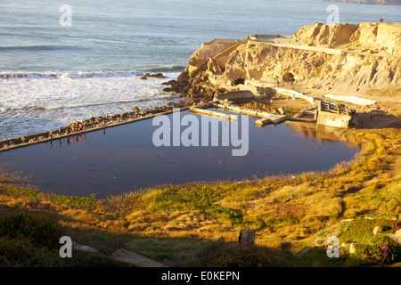 La gente a piedi in un singolo file linea lungo la parete del mare presso il bagno Sutro rovine a Lands End in San Francisco, California. Foto Stock