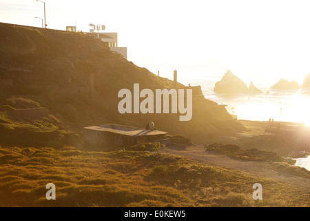 Due giovani amici di sesso femminile sedervi al sole presso il lungomare presso i bagni Sutro a Lands End in San Francisco, California. Foto Stock