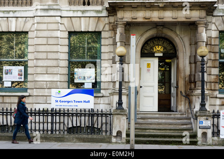 Una donna (motion sfocata) passando St George Town Hall, cavo Street, Tower Hamlets. Foto Stock