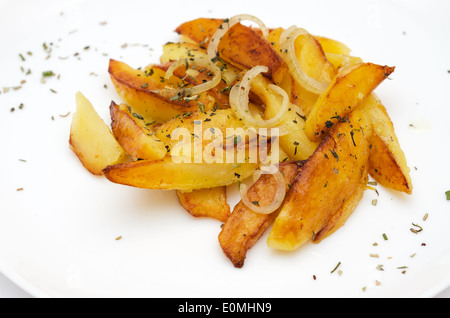 Patate arrosto cunei guarnita con erbe su piastra bianca di close-up. Foto Stock