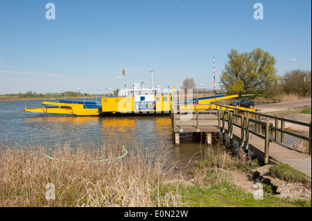 Traghetto giallo nel paesaggio fluviale Ormeggiata al pontile sull argine Foto Stock