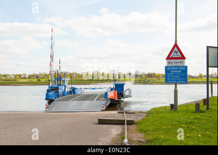 Traghetto blu nel paesaggio fluviale ancorata al luogo di sbarco sull argine Foto Stock