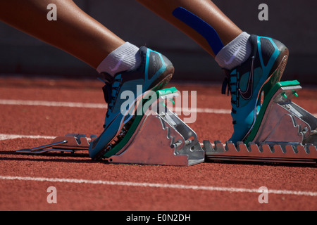 Donna africana di corridori americani in piedi in una serie di blocchi di partenza su una via di corsa la linea di partenza California USA Foto Stock