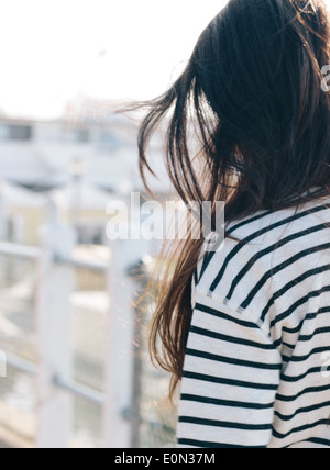 Donna con capelli scuri e camicia striscia passeggiando in una marina. Foto Stock