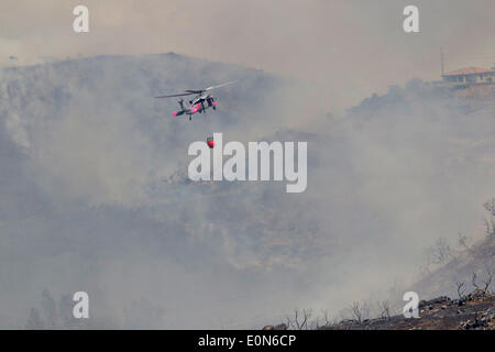 Un US Marine Corps HH-60H Sea Hawk elicottero porta un monsone di benna riempita con acqua per aiutare a combattere le isole Cocos wildfire come esso brucia la pedemontana distruggendo home maggio 15, 2014 intorno a San Marcos, California. Le evacuazioni forzate oltre 13.000 persone dalle loro case come il fuoco bruciavano attraverso San Diego County. Foto Stock