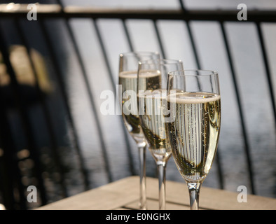 Tre bicchieri di champagne in una fila su un tavolo di legno Foto Stock